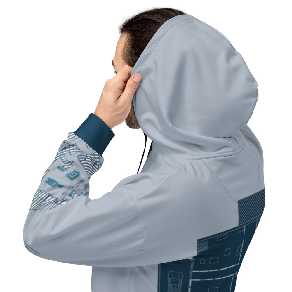 Man in a light blue hoodie, seen from the side, holding the hood. The hoodie features dark blue architectural blueprint patte