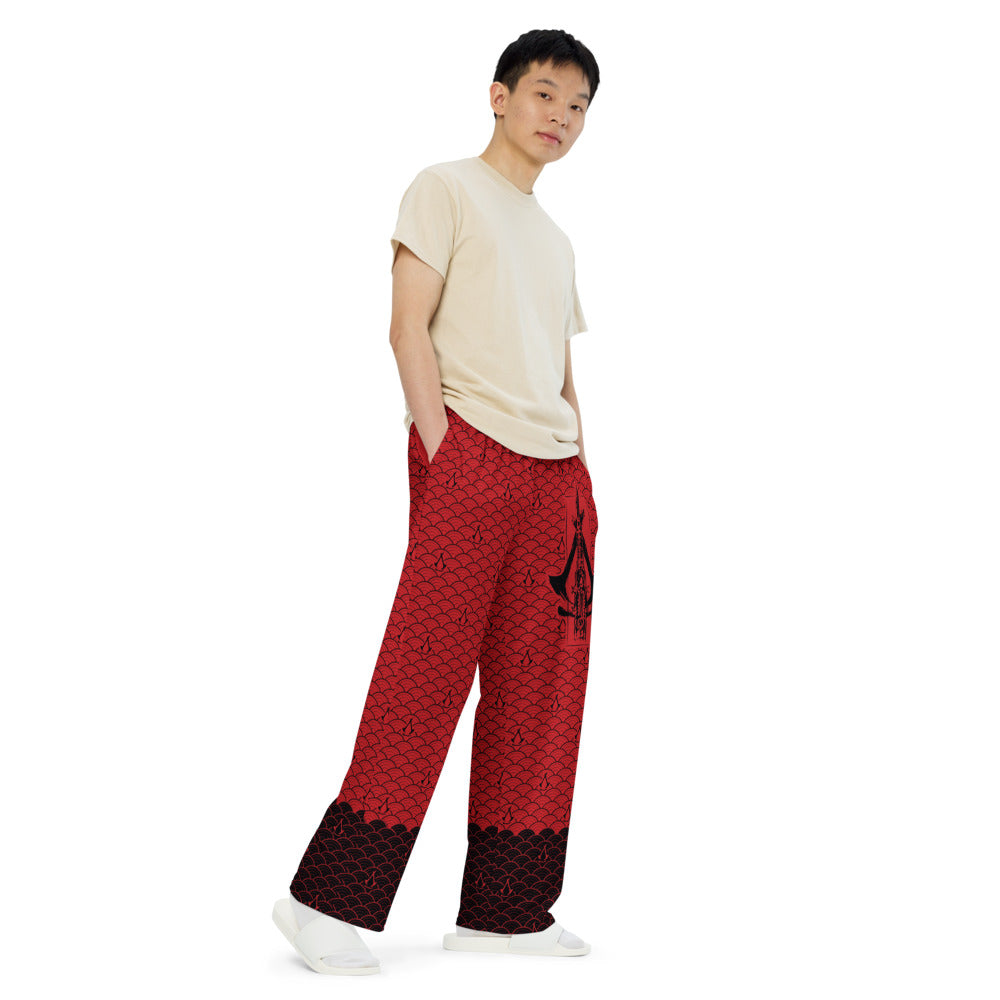 Red wide-leg pants with a repeating black scale pattern, a large black Assassin's Creed logo, and black cuffs.