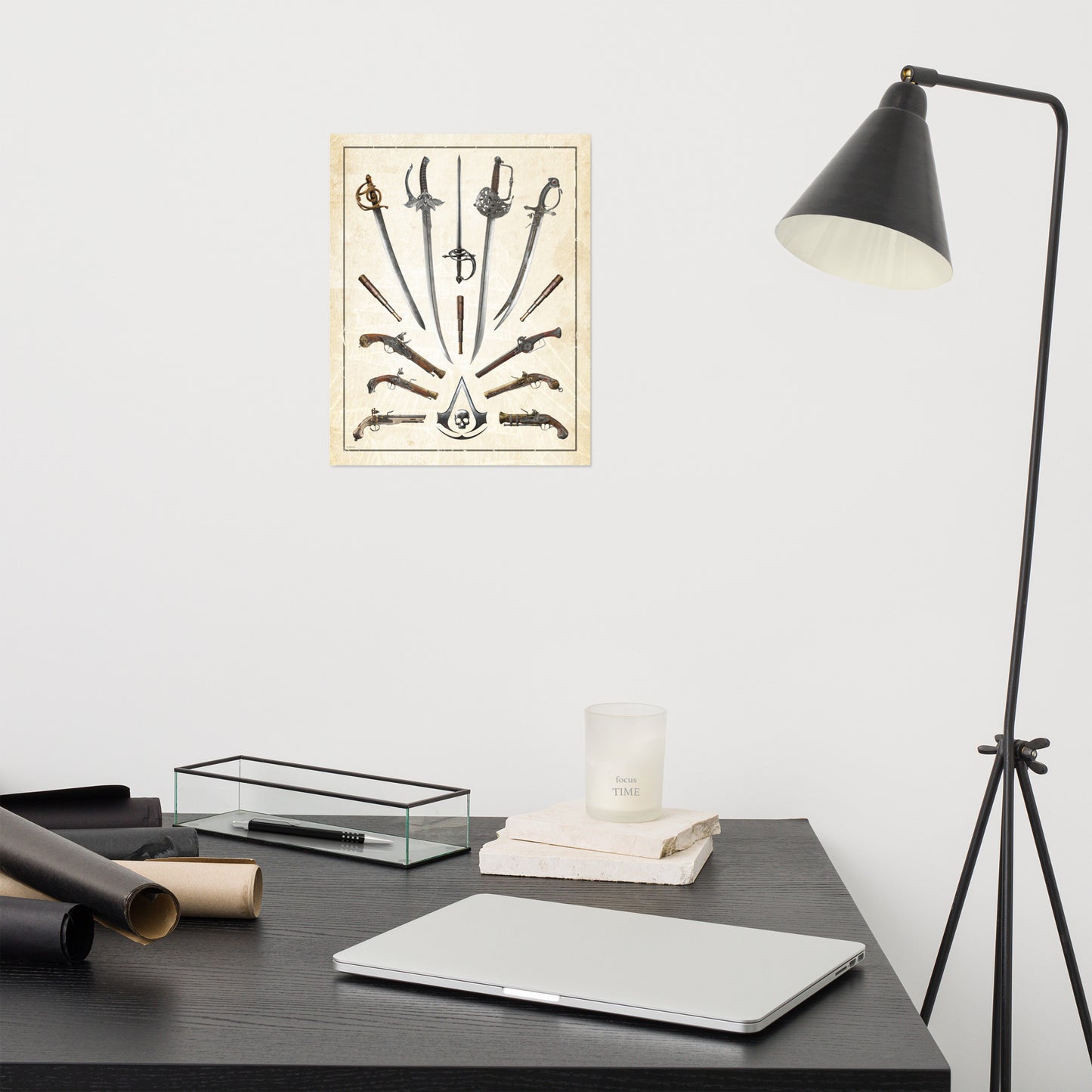 A poster of swords, pistols, and an Assassin's Creed skull logo hangs on a white wall above a dark desk with a laptop, candle