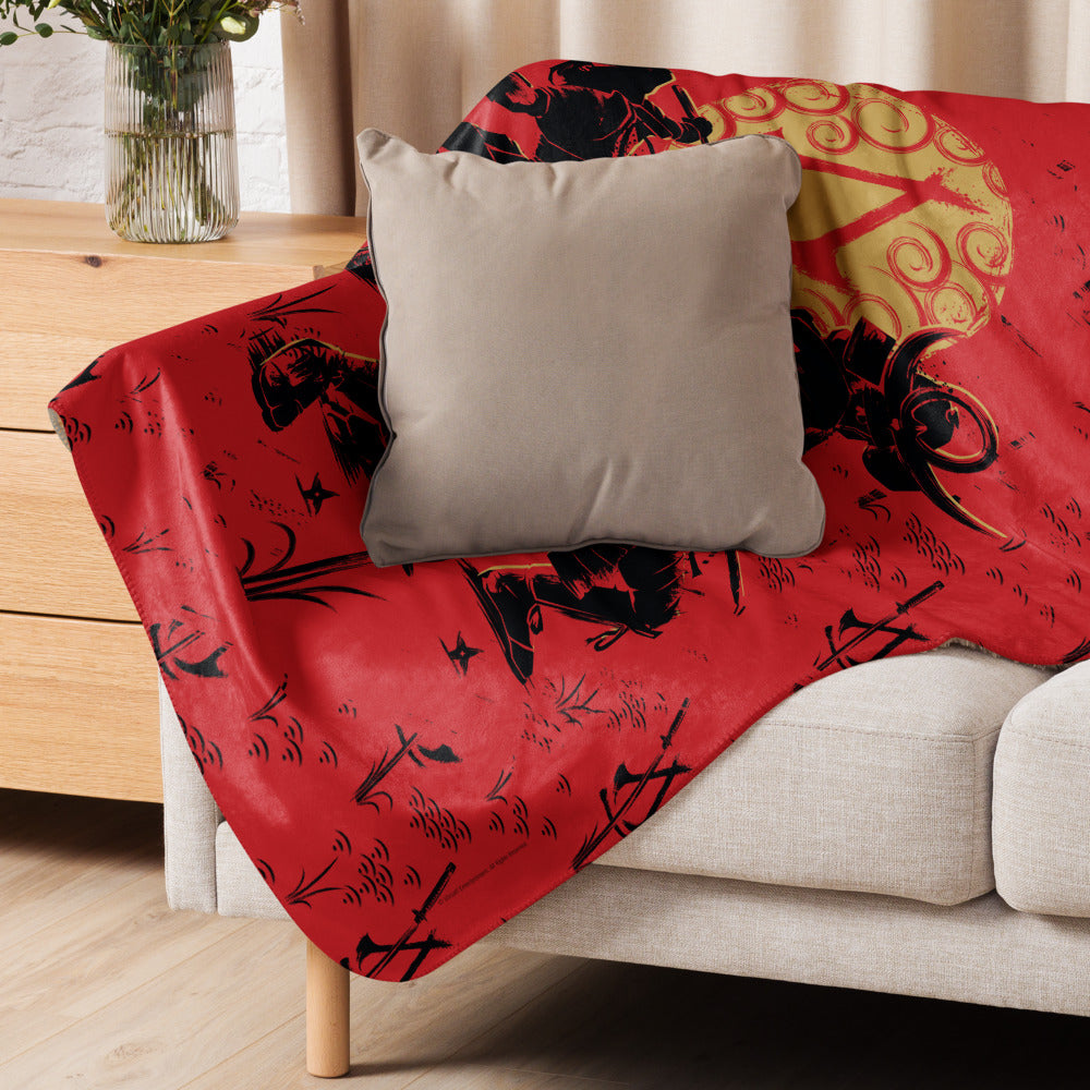 Red blanket displays a bold black & gold print of samurai warriors, various weapons, and a prominent swirling golden sun.
