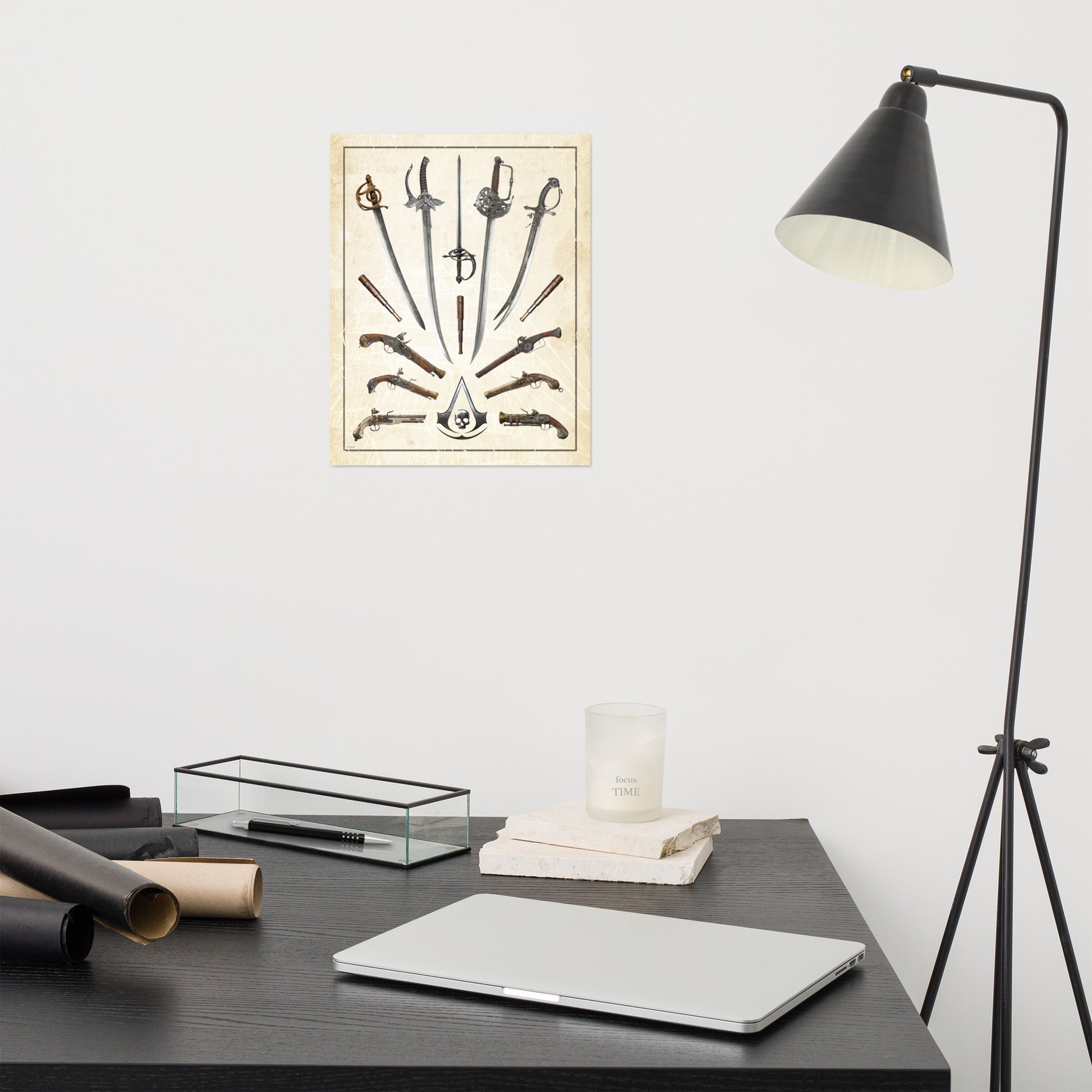 A poster of swords, pistols, and an Assassin's Creed skull logo hangs on a white wall above a dark desk with a laptop, candle