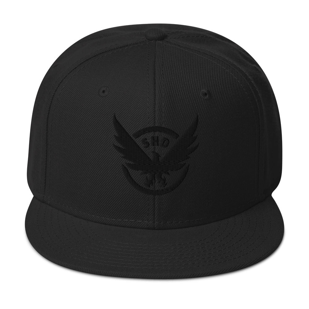 Black adjustable snapback hat with a prominent gold and red embroidered SHD Phoenix Crest. Features a grey under visor.
