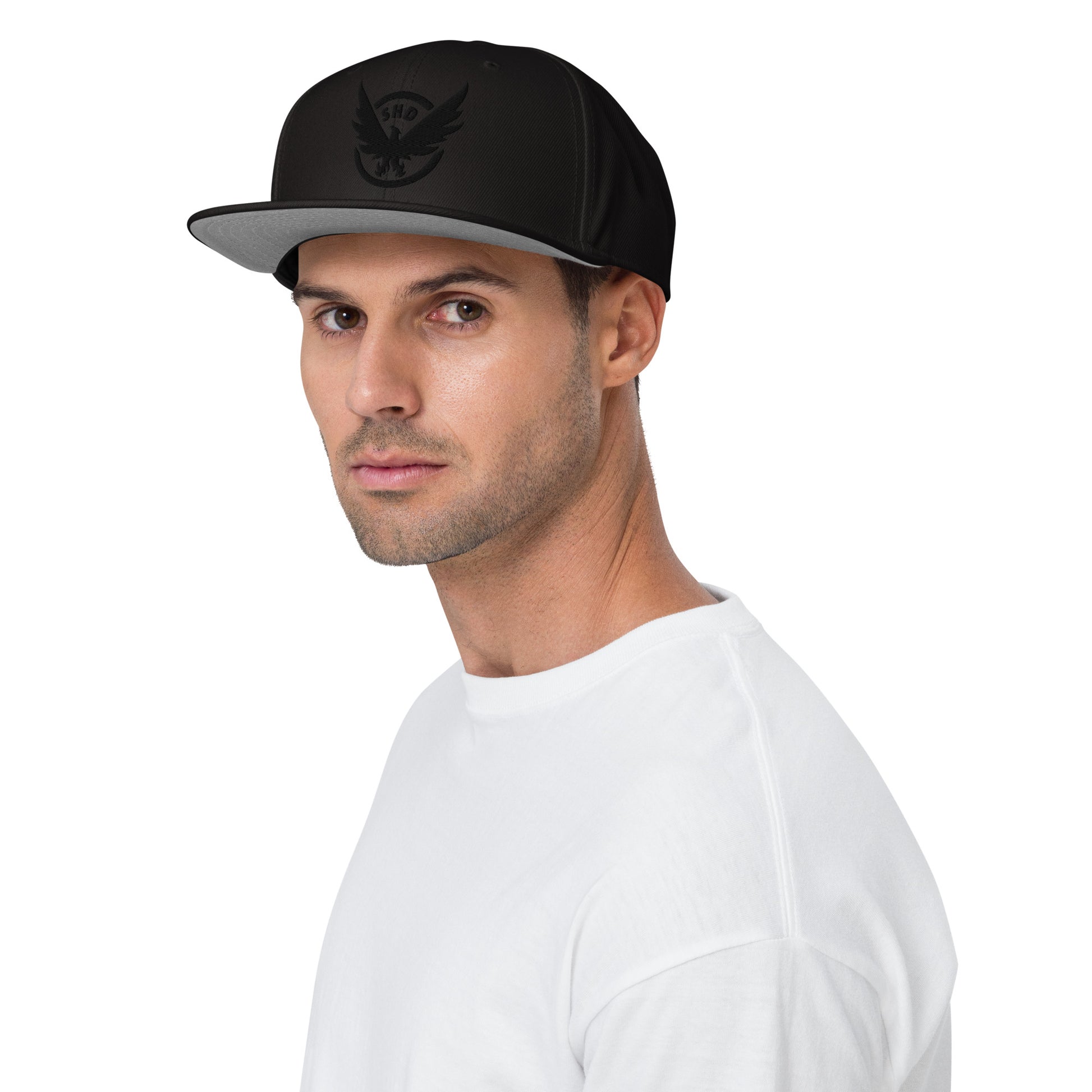 Black adjustable snapback hat with a prominent gold and red embroidered SHD Phoenix Crest. Features a grey under visor.