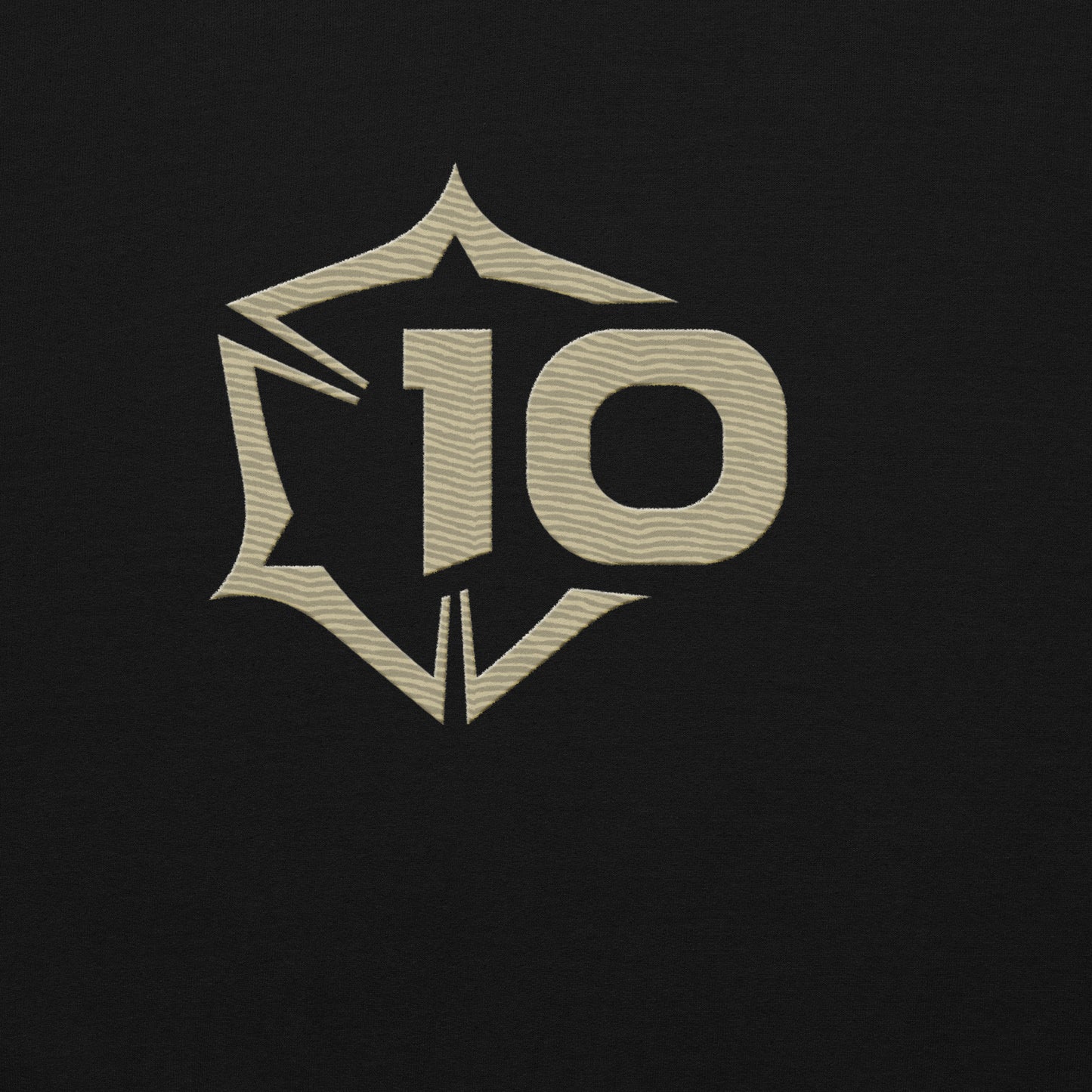 Embroidered beige shield-like logo on black fabric, featuring the number 10 with a wavy texture.